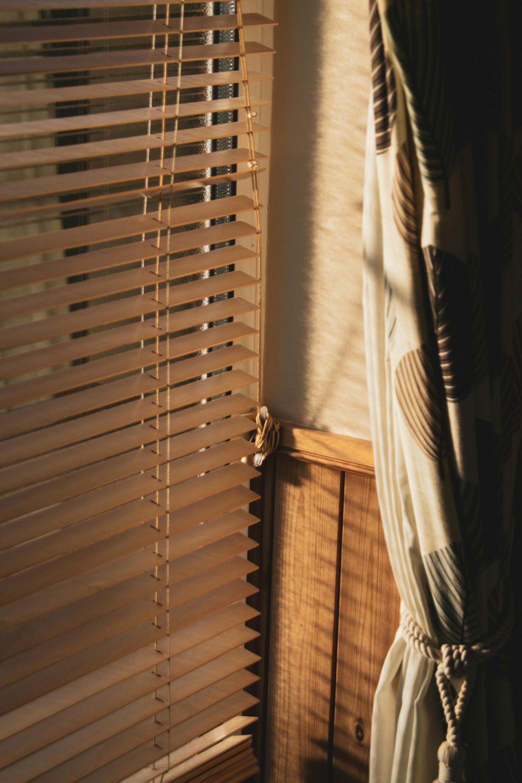Blinds letting light into a room, with the curtain pulled to the side, representing blinds vs curtains