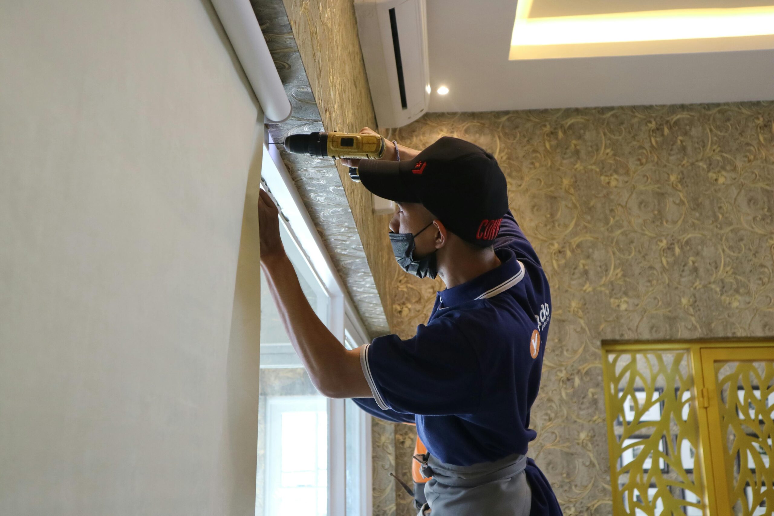 Homeowner with a drilling machine, installing their own blinds, representing DIY Window Blinds Installation.