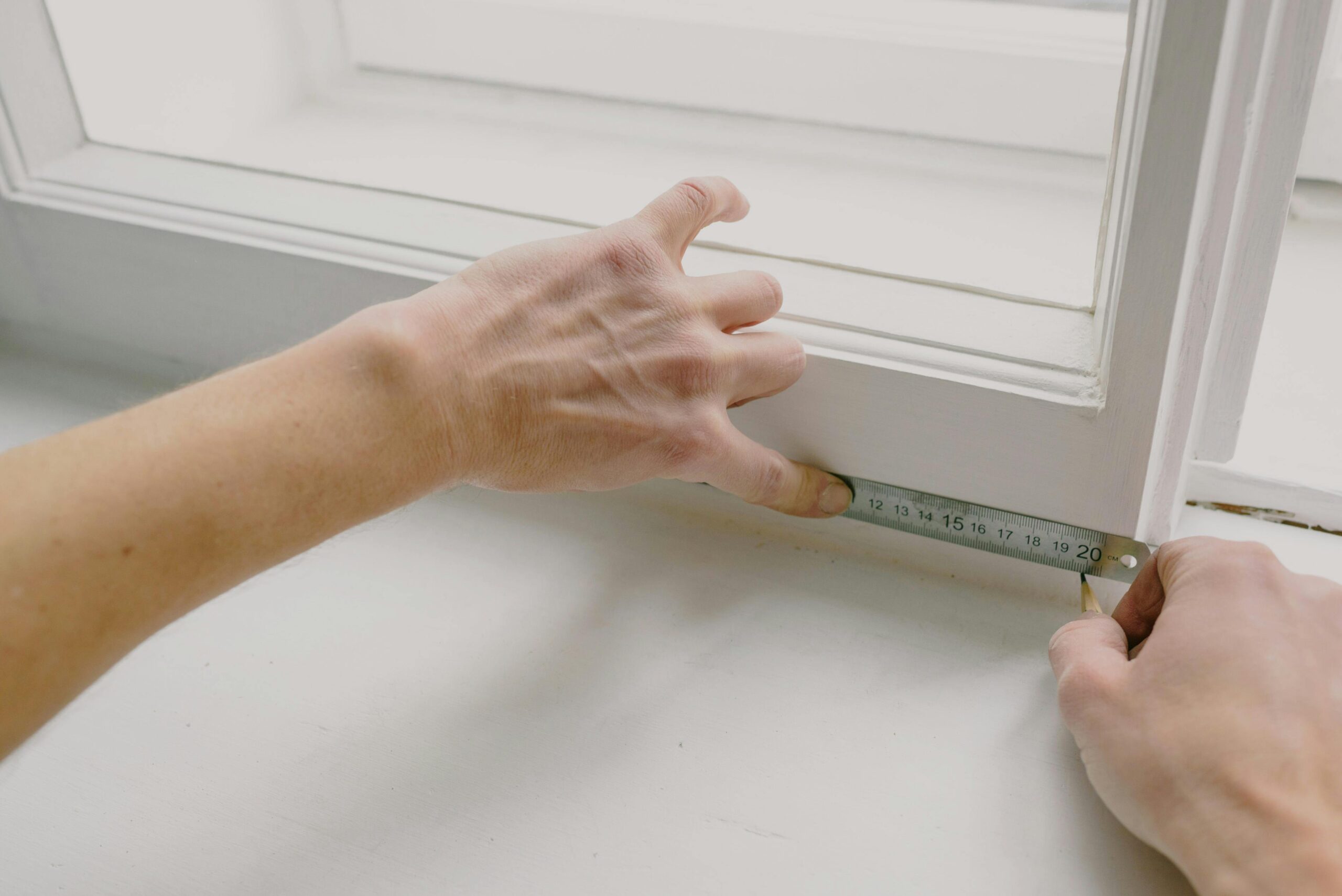 Hands with a measuring tape, measuring blinds, representing how to measure windows for blinds.